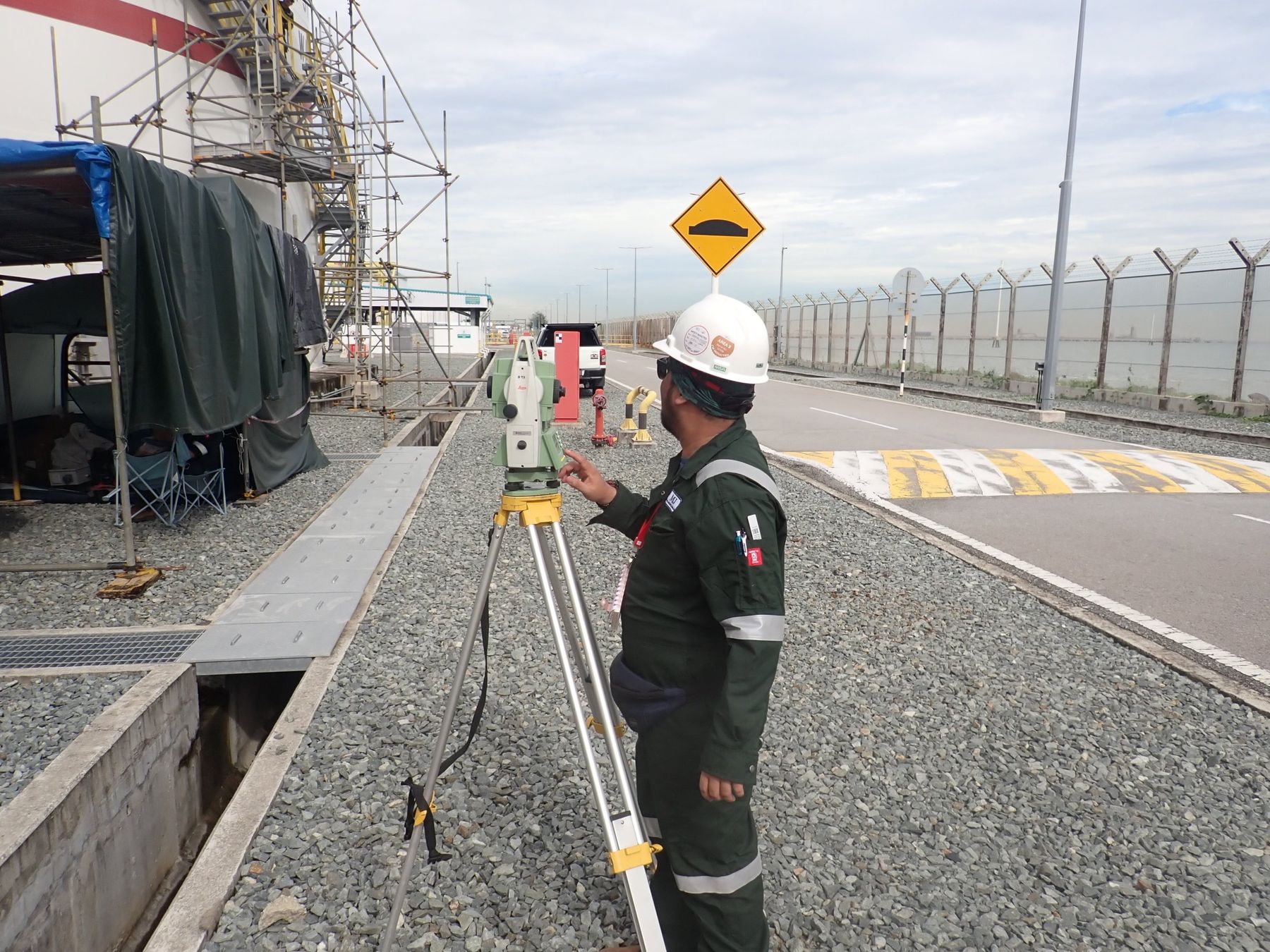 Wavewurk surveyor operating a total station beside a storage tank